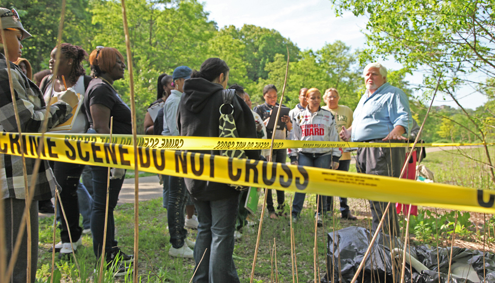 Pictured is Assistant Professor Edward Strimlan, M.D., conducting a mock crime scene investigation with forensic science students in Schenley Park. | Photo by Andy Weier